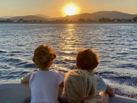 Two children enjoy a beautiful sunset view from the boat, creating a perfect family moment on the water.