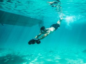 A swimmer dives underwater, exploring the vibrant marine life in crystal-clear waters — a perfect moment for snorkeling enthusiasts.