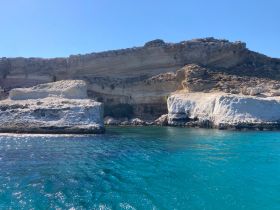 A stunning view of a rugged coastline with crystal-clear waters, perfect for exploring by boat or enjoying a scenic cruise.
