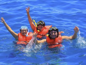 A joyful group of snorkelers splashes in the vibrant blue waters, showcasing the excitement of underwater adventures and fun in the sun.