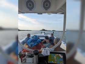 A group of friends relaxes on a boat, enjoying the scenic views as they navigate through calm waters — perfect for a day of adventure and exploration.