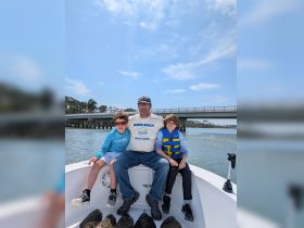 A father and his two children enjoy a day on the water, showcasing the joy of family fishing trips aboard their boat.