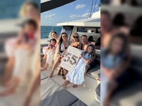 A joyful family celebrates a 55th birthday aboard a boat, showcasing a festive atmosphere with a personalized birthday sign.