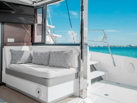 A stylish interior view of a boat's cabin featuring comfortable seating and large windows, perfect for enjoying the scenic ocean views.