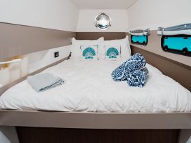 Cozy interior cabin featuring a comfortable bed with decorative pillows and neatly arranged towels, perfect for relaxation on a boat.
