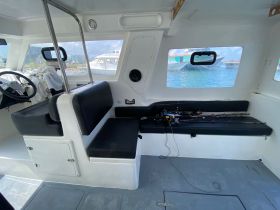 Interior view of a boat's cabin featuring seating and a helm, ideal for fishing trips or leisurely cruises.