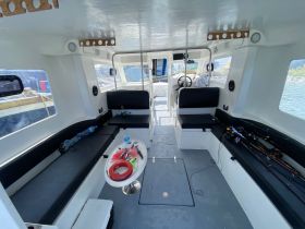 Interior view of a spacious boat cabin featuring comfortable seating and fishing gear, perfect for a day out on the water.