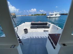 Interior view of a boat's seating area, showcasing comfortable black cushions and a clean, spacious layout — ideal for relaxing while cruising.