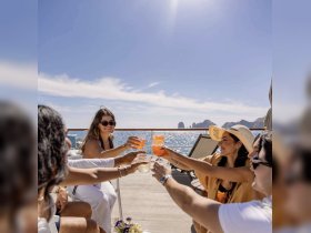 A joyful group toasts with cocktails on the deck of a boat, celebrating under the sun with stunning ocean views — perfect for memorable gatherings and special occasions.