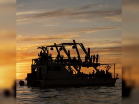A lively group enjoys a sunset celebration aboard a boat, silhouetted against a vibrant sky — perfect for memorable gatherings on the water.