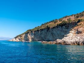 A stunning view of a serene coastline with boats anchored in clear blue waters, perfect for exploring hidden coves and enjoying the beauty of nature.