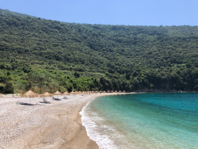 A serene beach scene featuring sun loungers and crystal-clear waters, perfect for relaxation and enjoying nature's beauty.