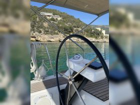 A close-up view of the helm and steering wheel on a boat, showcasing the sleek design and functionality of the console, perfect for navigating serene waters.