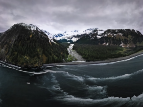 A breathtaking aerial view of a rugged coastline surrounded by snow-capped mountains, showcasing the stunning natural beauty of the landscape.
