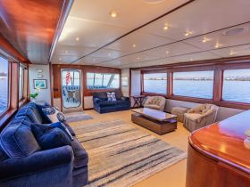 A spacious and elegantly designed interior lounge area of a yacht, featuring comfortable seating and large windows offering stunning views of the water.