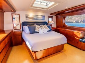A beautifully designed cabin featuring a cozy bedroom with elegant furnishings and a scenic view through the window, perfect for relaxing on a boat getaway.