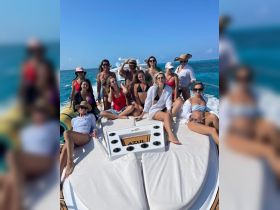 A lively group of friends enjoys a fun day on a yacht, soaking up the sun and celebrating together in stylish swimwear.