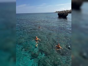 A group of friends enjoys a refreshing swim in crystal-clear waters, showcasing the perfect adventure for snorkeling and ocean exploration.