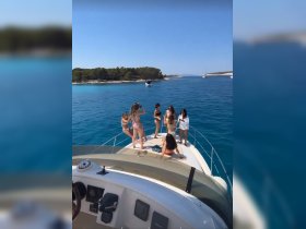 A lively group of friends enjoys a fun day on the boat, celebrating under the sun with clear blue waters in the background — perfect for summer adventures.