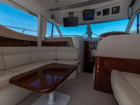 Interior view of a luxurious boat cabin featuring comfortable seating and a helm, perfect for relaxing or navigating on the water.