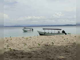 Two boats are anchored near a sandy beach, showcasing a serene coastal scene perfect for exploring the waters.