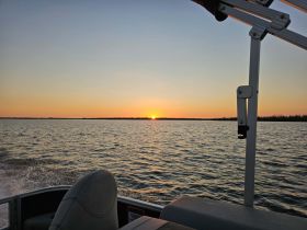 A serene sunset view from a boat, showcasing the tranquil waters and a beautiful horizon — perfect for evening cruises.