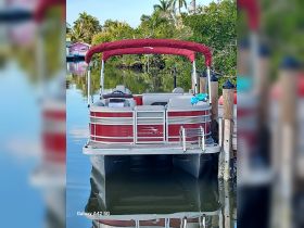A serene view of a Bennington pontoon boat docked in calm waters, surrounded by lush greenery — perfect for leisurely outings and family gatherings.