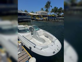 A sleek speedboat docked at a vibrant waterfront, showcasing its stylish design and comfortable seating — perfect for a day on the water.