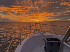 A stunning sunset view from the bow of a boat, showcasing the vibrant colors reflecting on the water — perfect for evening cruises.