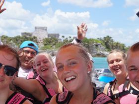 A joyful group of friends enjoying their boat trip near Tulum, Mexico, showcasing smiles and excitement against a beautiful backdrop.