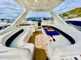 A stylish interior view of a yacht's lounge area, featuring comfortable seating and a dining table, perfect for relaxing and entertaining on the water.