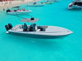 A fishing boat navigates through stunning turquoise waters, with a captain at the helm, showcasing the beauty of a vibrant marine environment.
