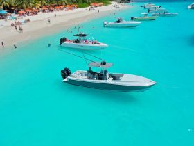 A vibrant scene at a beach with multiple boats anchored in stunning turquoise waters, showcasing a lively atmosphere of fun and relaxation.