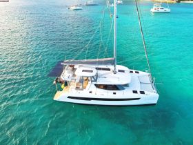 A stunning aerial view of a sleek catamaran cruising through crystal-clear turquoise waters, perfect for luxury charters and island adventures.