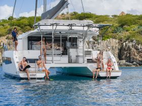 A lively group enjoys a day on a catamaran, with some preparing for snorkeling while others relax at the water's edge — a perfect scene for adventure and fun on the water.