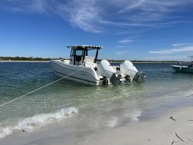 A sleek speedboat is docked on a sandy shore, showcasing its modern design against a clear blue sky — perfect for day trips and water adventures.
