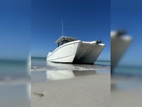 A striking view of a sleek speedboat resting on the sandy shore under a clear blue sky, perfect for a day of adventure on the water.