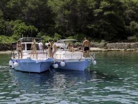A lively group enjoys a day on the water, relaxing on their boats and soaking up the sun — perfect for summer adventures and beach outings.