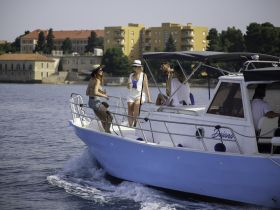 A lively group enjoys a sunny day on a boat, sipping drinks and celebrating the summer vibes — perfect for memorable outings on the water.