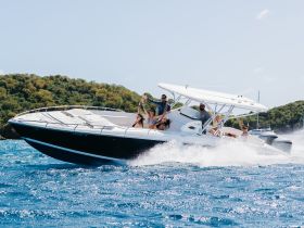 A lively group enjoys a thrilling ride on a speedboat, celebrating the joy of being on the water with friends against a scenic backdrop.