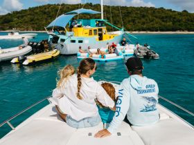 A family enjoys a day on the water, taking in the vibrant scenery and fun atmosphere with multiple boats and activities in the background.