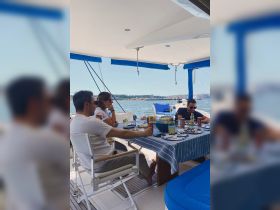 A group enjoys a delightful meal on the deck of a boat, surrounded by beautiful water views — perfect for social gatherings and dining experiences on the water.