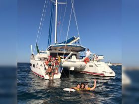 A joyful group enjoys a fun day swimming around a catamaran, creating unforgettable memories on the water with family and friends.