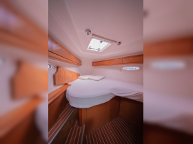 A cozy cabin interior featuring a comfortable bed and storage space, perfect for relaxing on a boat getaway.