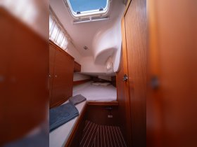 A cozy cabin interior of a boat featuring a comfortable sleeping area and storage, perfect for relaxing during a sailing trip.