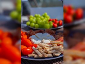 A beautifully arranged charcuterie platter featuring fresh tomatoes, grapes, and cheese, perfect for enjoying on a boat trip. Ideal for catering or casual dining while cruising.