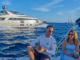 A couple enjoys a scenic boating experience on the ocean, with a luxurious yacht cruising in the background — perfect for memorable sailing adventures.