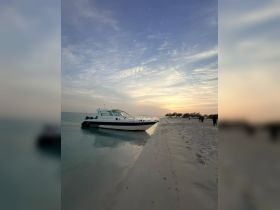 A sleek boat is docked on a serene beach at sunset, creating a picturesque scene perfect for evening cruises or relaxation by the water.