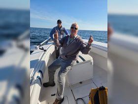 Two men enjoy a day on the water, giving thumbs up while aboard a boat — a perfect moment of camaraderie and adventure.