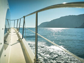 A stunning view of a boat cutting through calm waters, showcasing the sleek design and beautiful coastal scenery in the background.